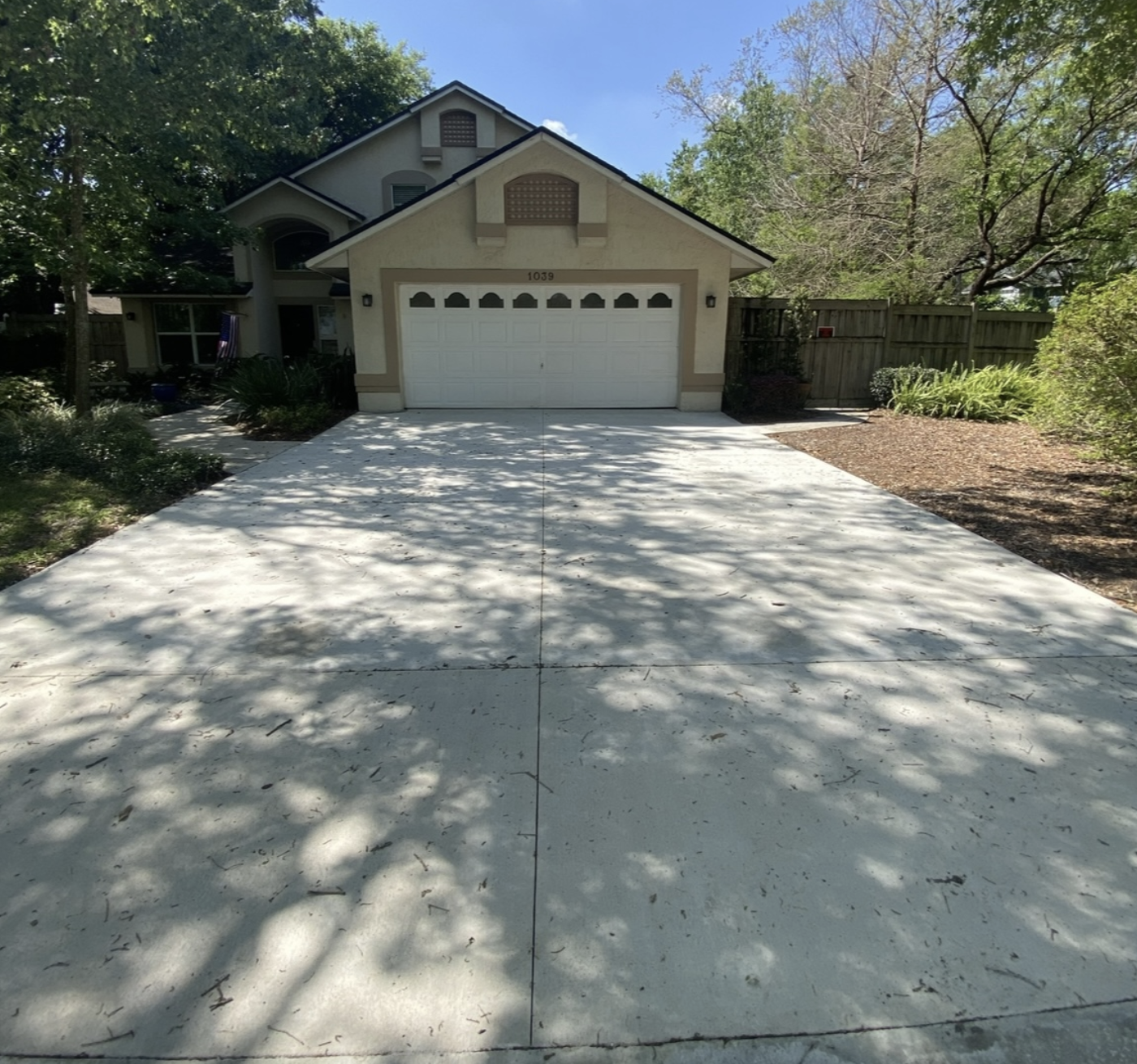 Concrete driveway installation in residential setting, showcasing clean surface and adjacent landscaping, highlighting quality craftsmanship by Accu-Krete.