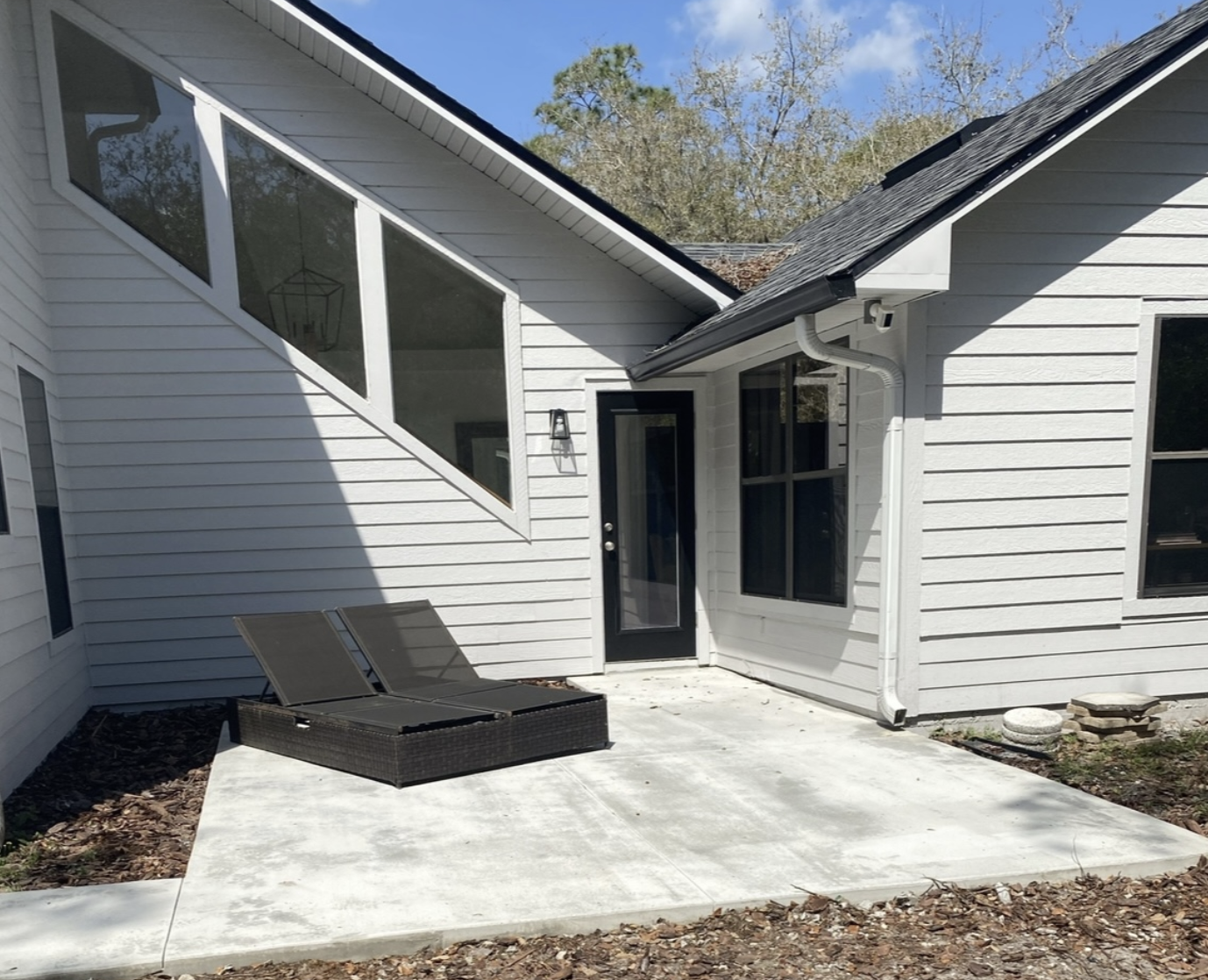 Concrete patio area with lounge chairs beside a modern home, showcasing quality craftsmanship and inviting outdoor space for relaxation and entertaining.
