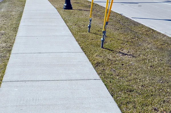 Concrete sidewalk with grass edge and utility poles, representing durable concrete solutions for residential and commercial projects by Accu-Krete.