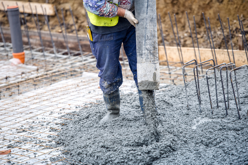 Construction worker pouring concrete into a foundation, showcasing commercial concrete solutions and craftsmanship for durable structures.